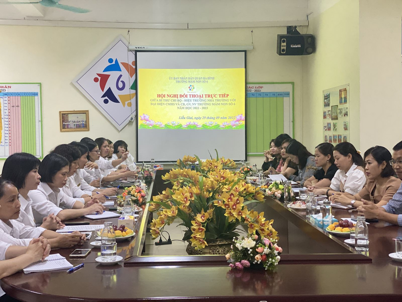 A group of people sitting at long tables in a room with a large screen
Description automatically generated with low confidence
