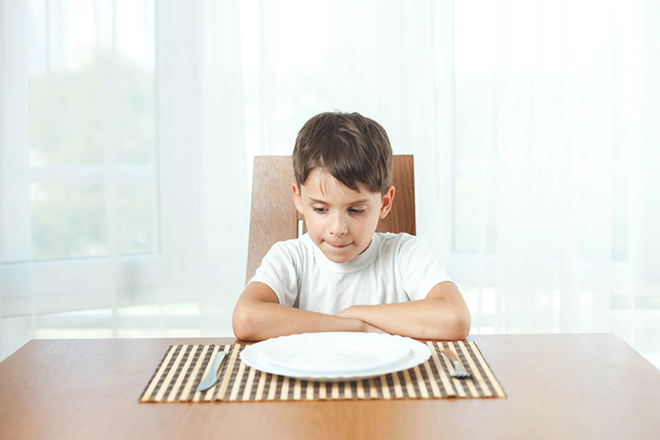 Bé trai ngồi tại bàn ăn