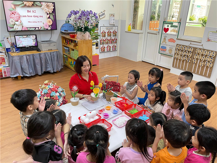 A group of children clapping and a person giving flowers to a group of kids

Description automatically generated