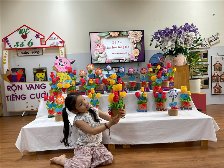 A child sitting on the floor holding a vase of flowers

Description automatically generated