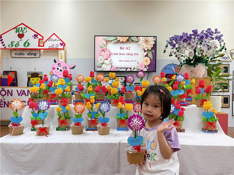 A child standing in front of a table with many colorful flowers

Description automatically generated