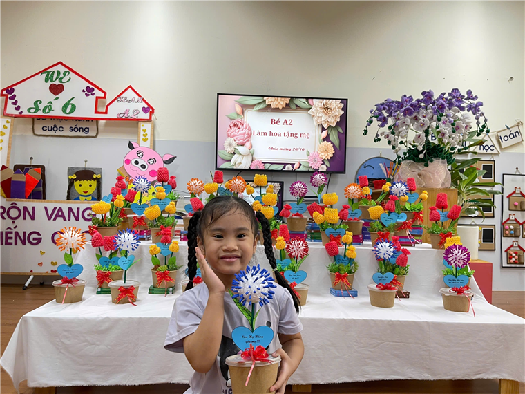 A child holding a flower in a pot

Description automatically generated