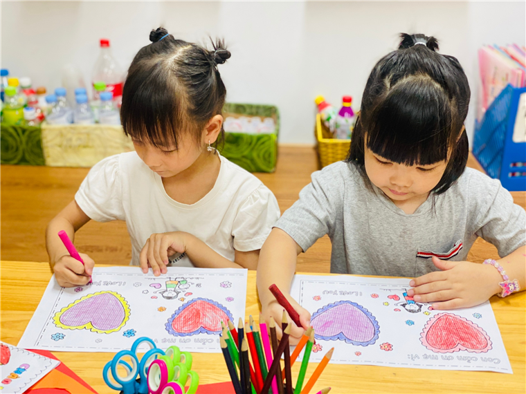 Two girls coloring on paper
Description automatically generated