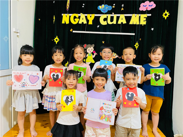 A group of children holding up paper
Description automatically generated