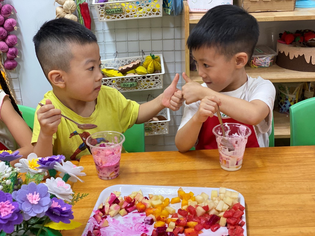 Two young boys sitting at a table with food
Description automatically generated