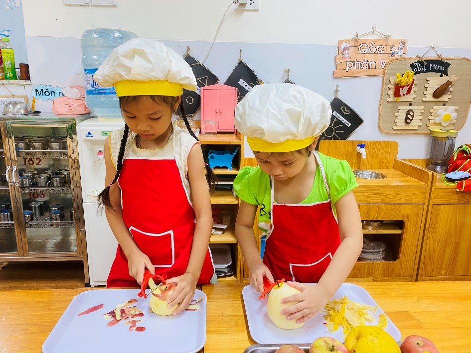 Two girls wearing chef hats and aprons preparing food
Description automatically generated