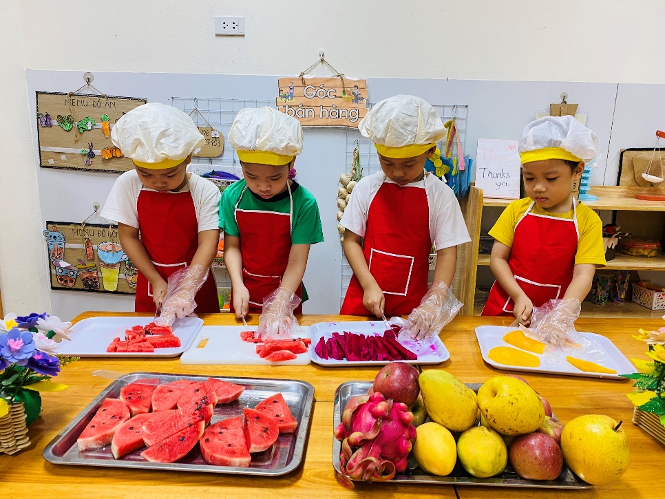 A group of children wearing aprons and hats preparing food
Description automatically generated