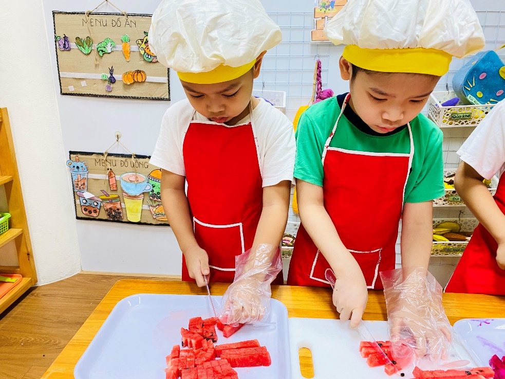 Two children in aprons cutting watermelon
Description automatically generated