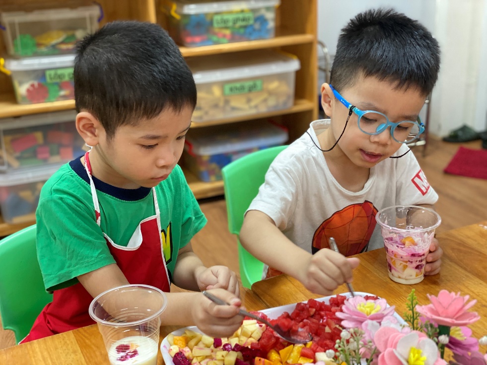 Two boys eating fruit at a table
Description automatically generated