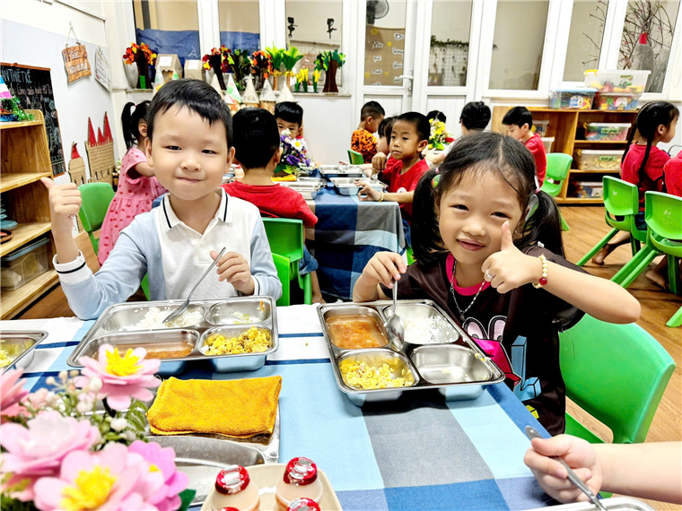 A group of children sitting at a table eating
Description automatically generated