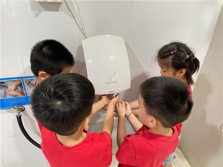 A group of children touching a white object
Description automatically generated