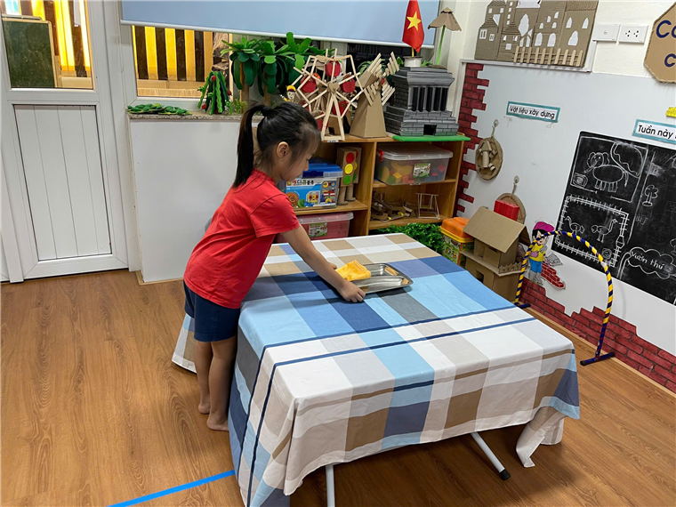 A child standing by a table
Description automatically generated