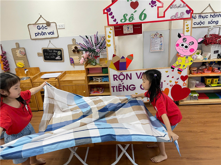 A child and child folding a blanket
Description automatically generated