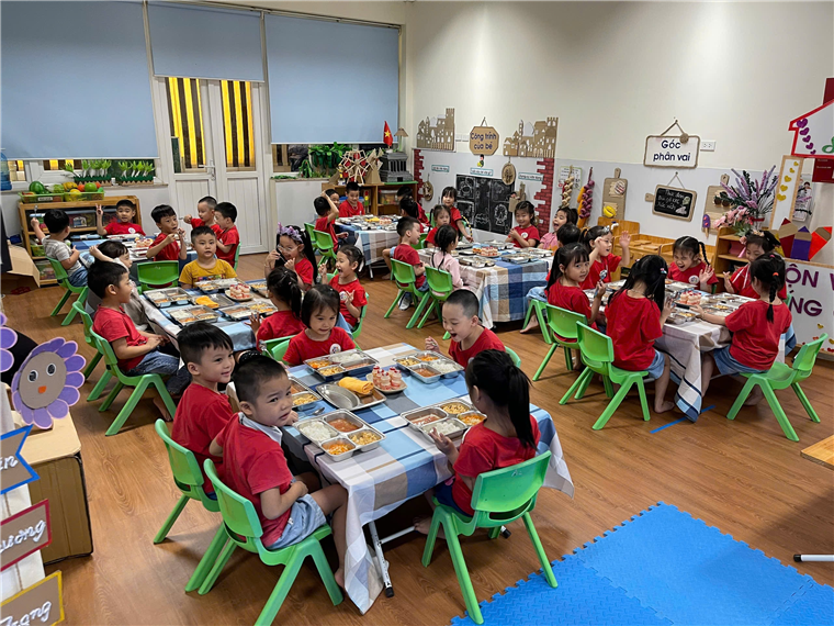 A group of children sitting at tables in a classroom
Description automatically generated