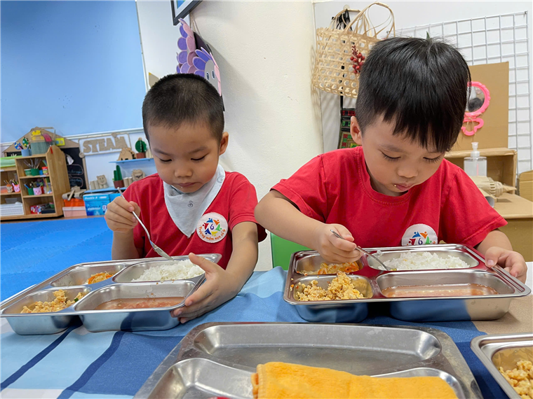 A couple of young boys eating food
Description automatically generated