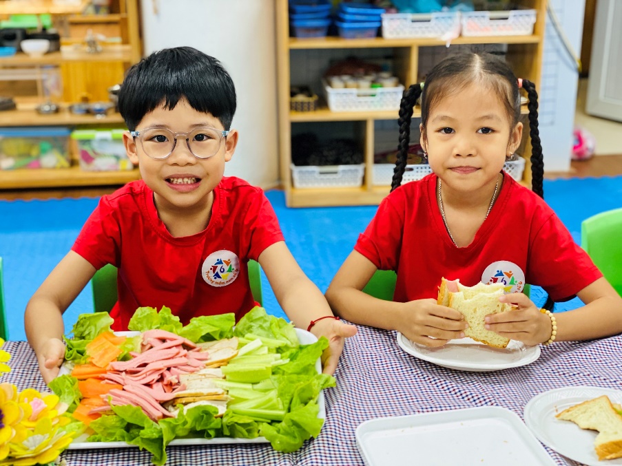 Two children sitting at a table with food
Description automatically generated