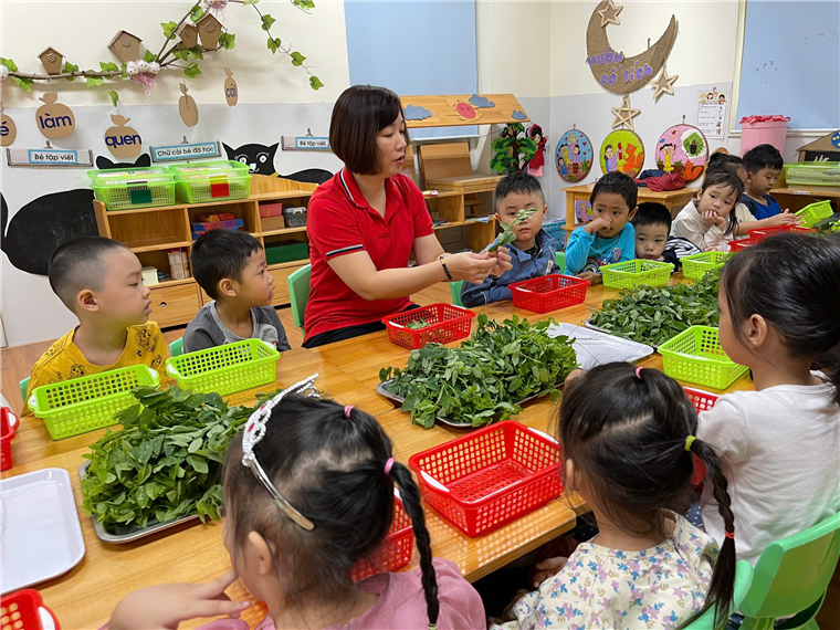A group of children sitting around a table with a person in a red shirt
Description automatically generated