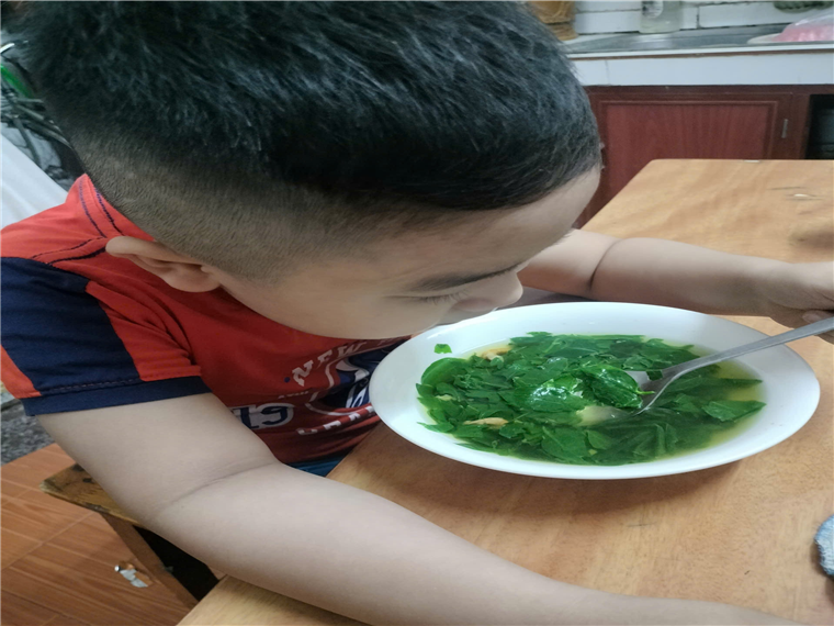 A child eating a bowl of soup
Description automatically generated