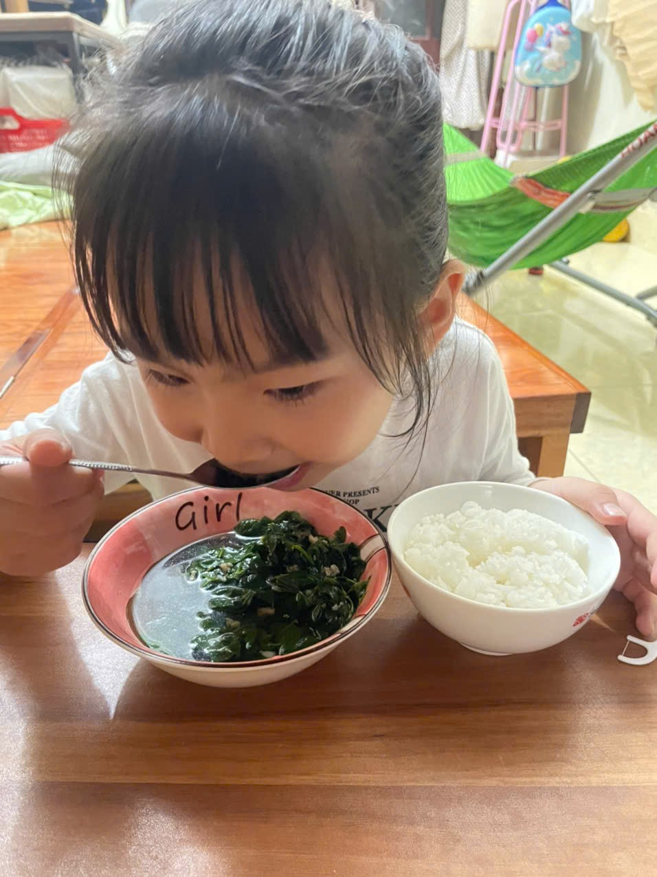 A child eating food with a spoon
Description automatically generated