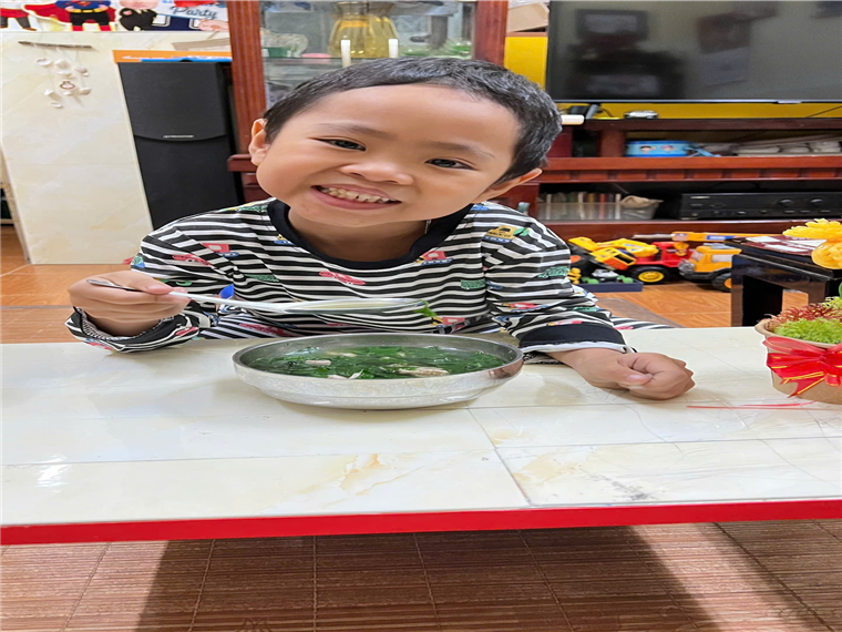 A child sitting at a table eating food
Description automatically generated