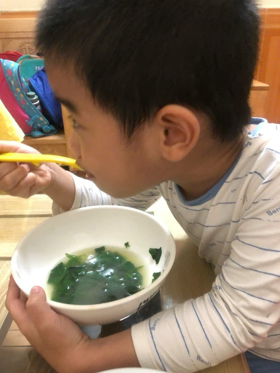 A child eating a bowl of soup
Description automatically generated