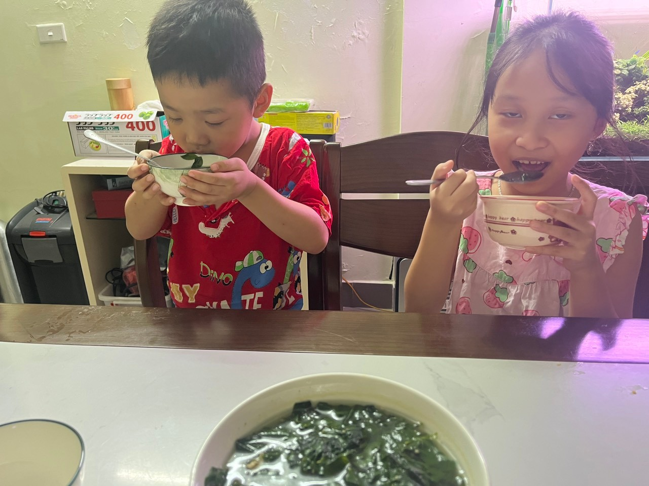 A child and child eating from bowls
Description automatically generated