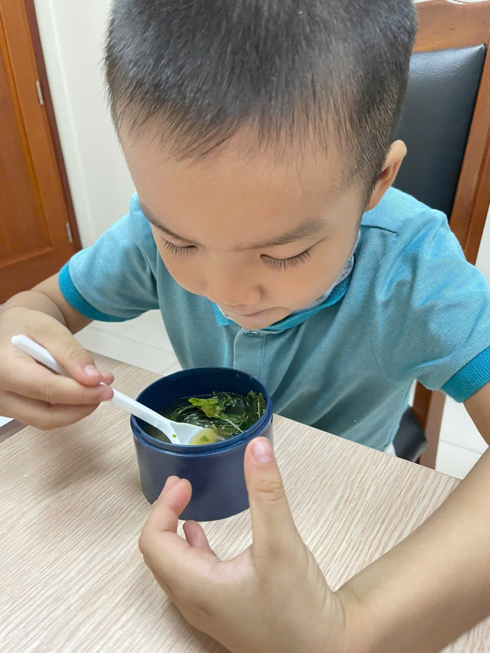 A child eating soup with a spoon
Description automatically generated