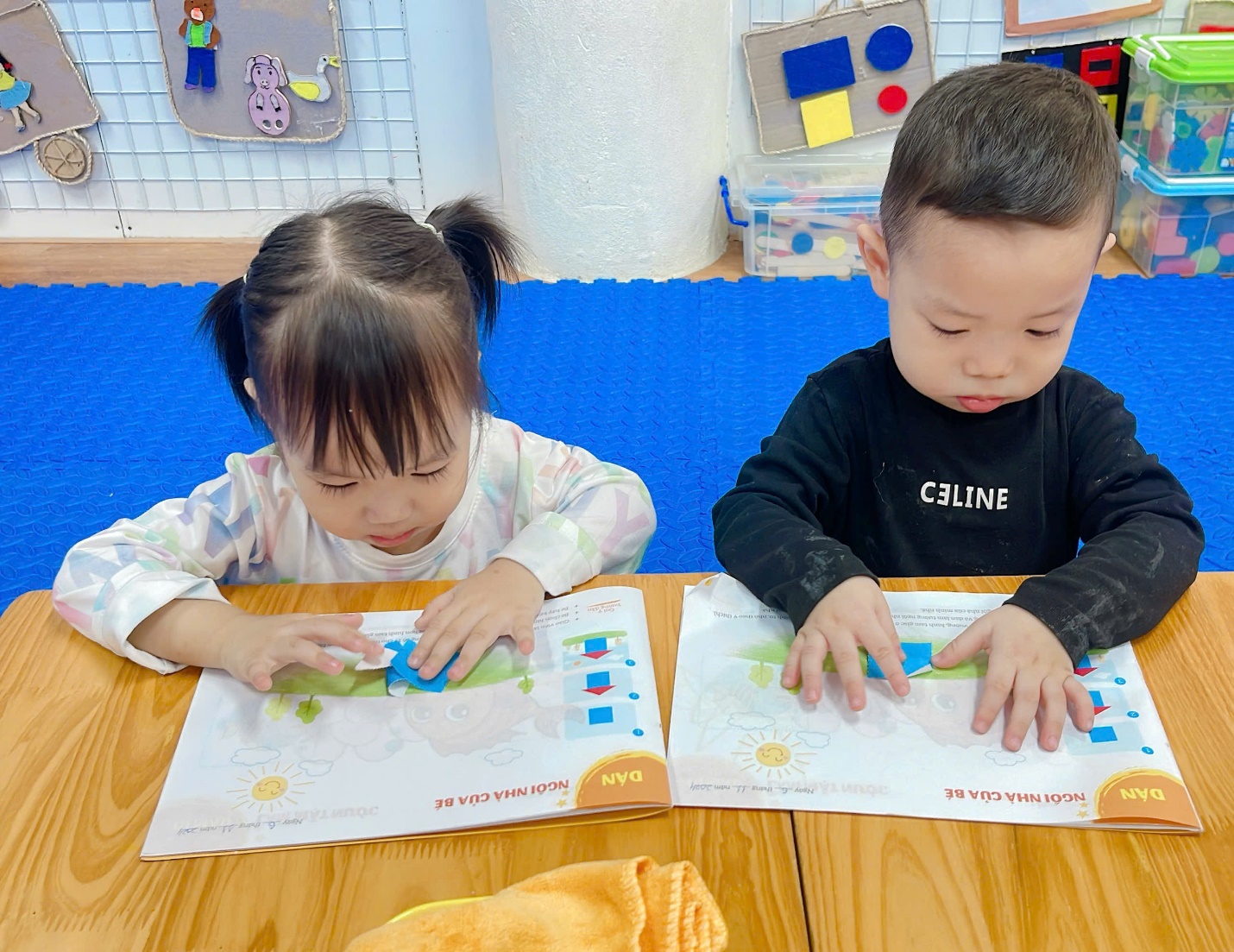 A child and child sitting at a table with books
Description automatically generated