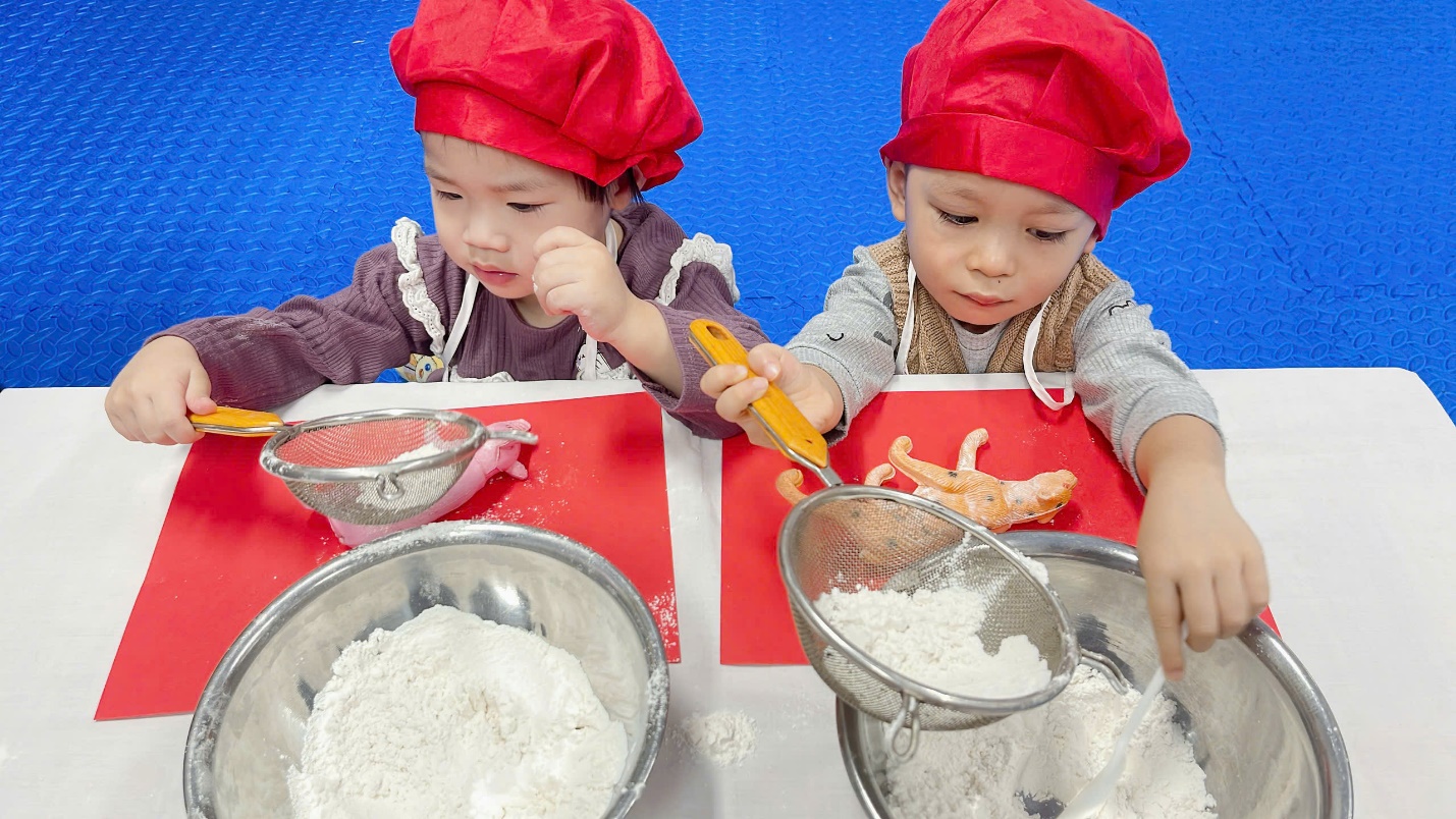 Two children in red hats and aprons

Description automatically generated