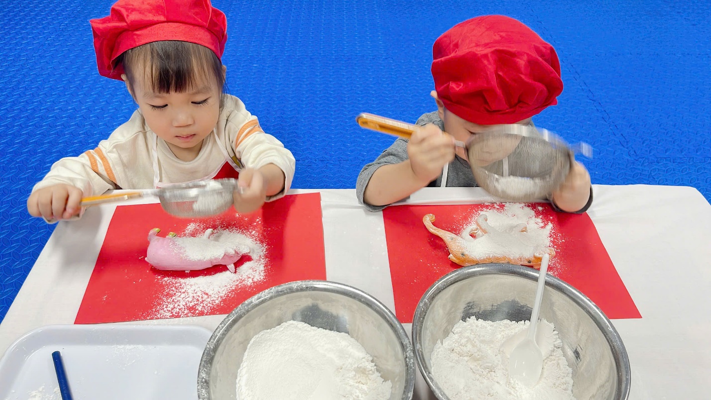 A couple of children in chef hats mixing flour

Description automatically generated