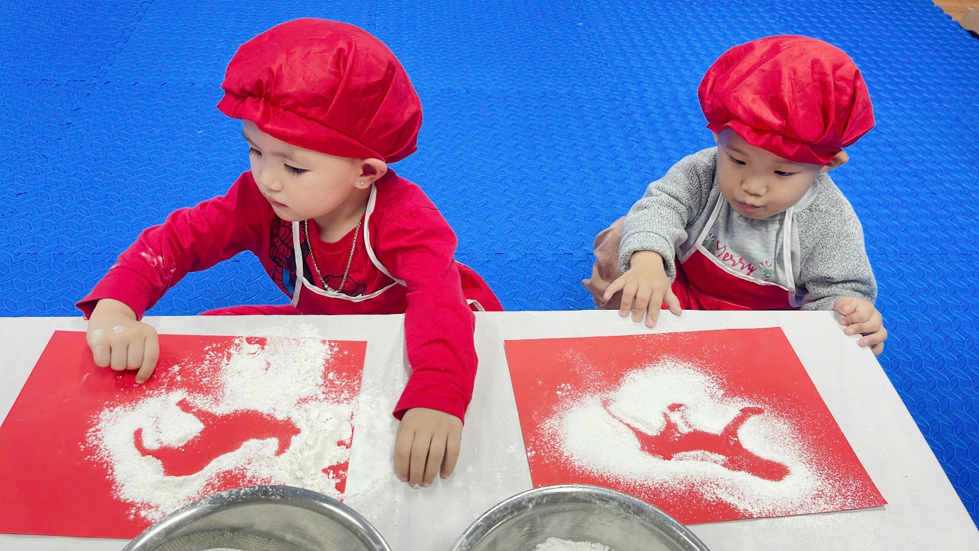 A couple of young children wearing red and white cooking outfits

Description automatically generated