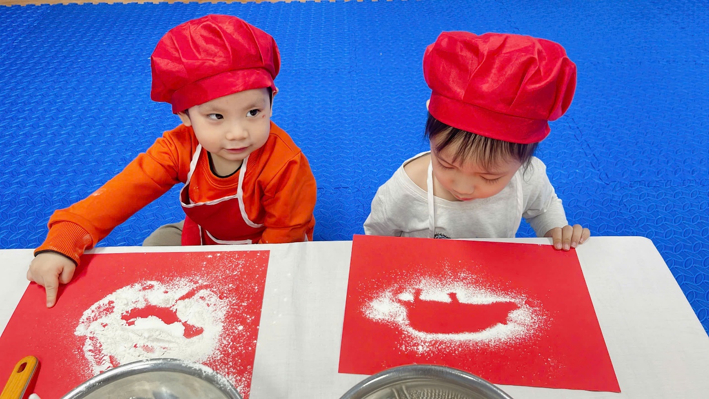 Two children wearing red hats and aprons

Description automatically generated