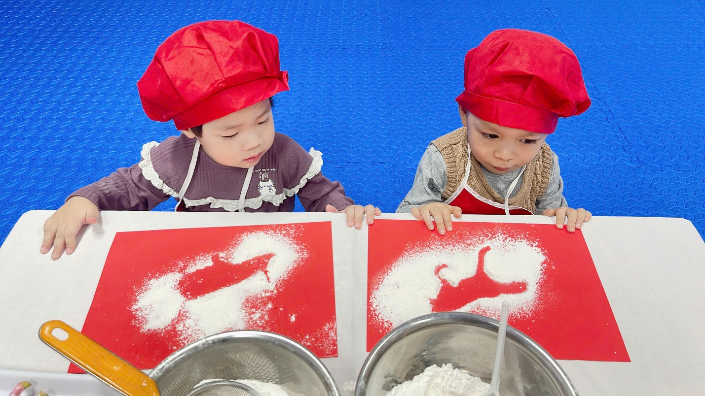 A couple of young children wearing red hats and aprons

Description automatically generated