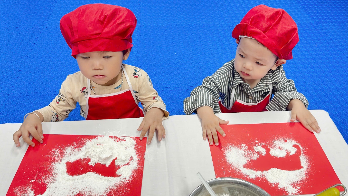 A couple of young children wearing red aprons and red hats

Description automatically generated