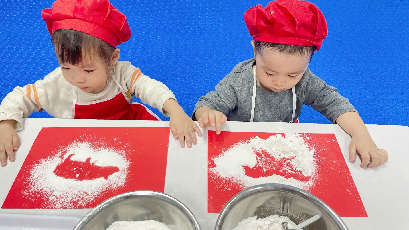 Two children wearing red hats and red aprons

Description automatically generated