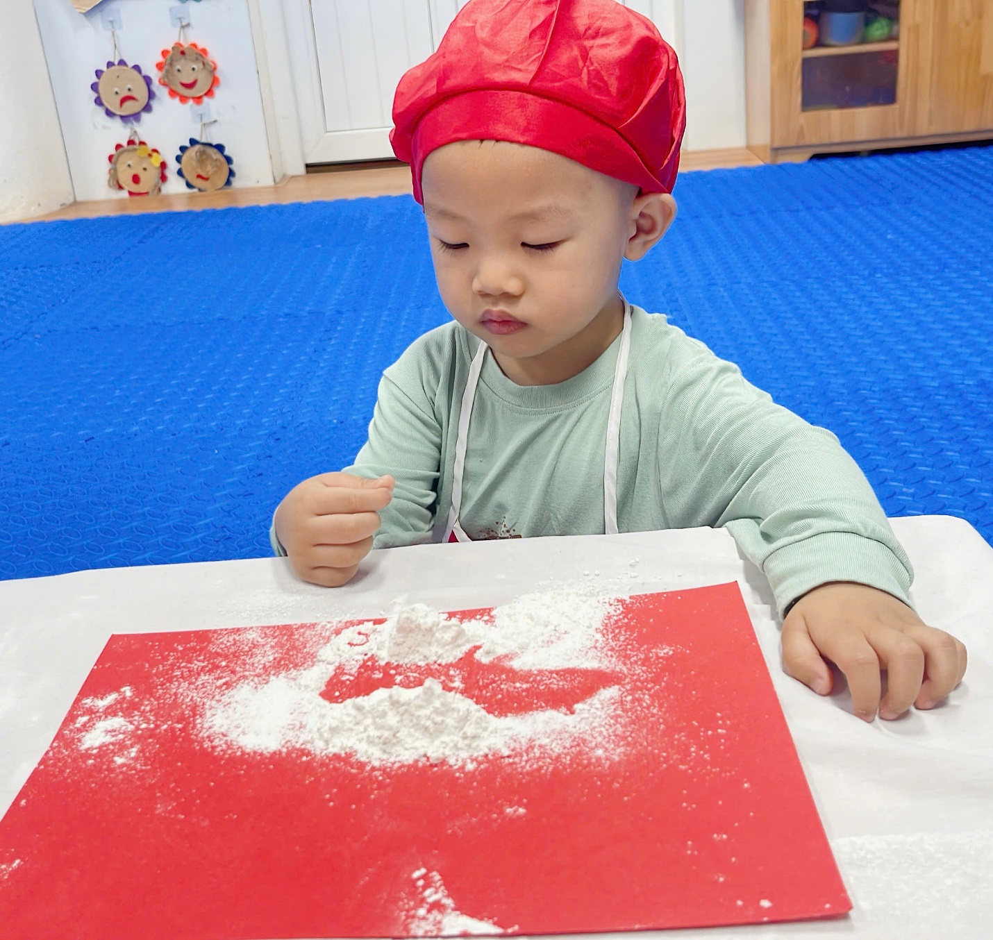 A child sitting at a table with flour on it

Description automatically generated