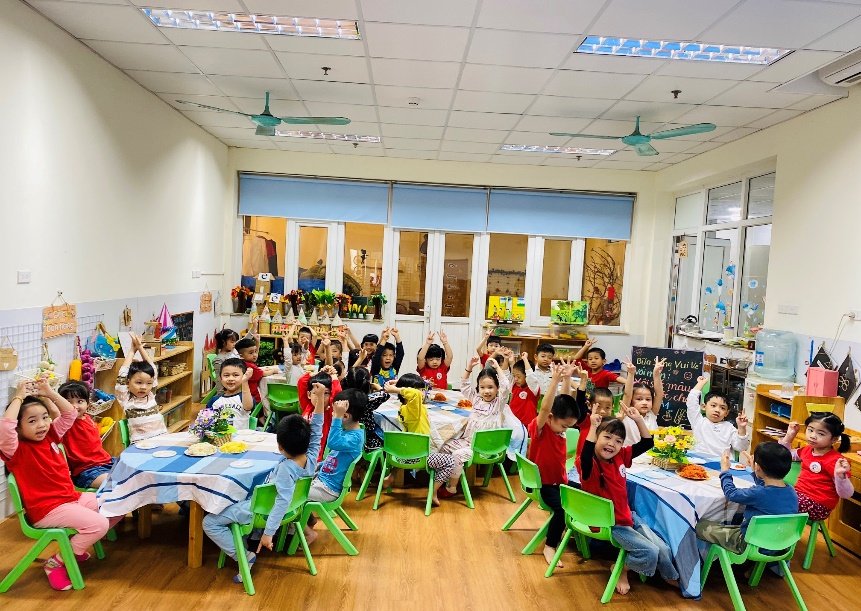 A group of children sitting at a table in a classroom

Description automatically generated