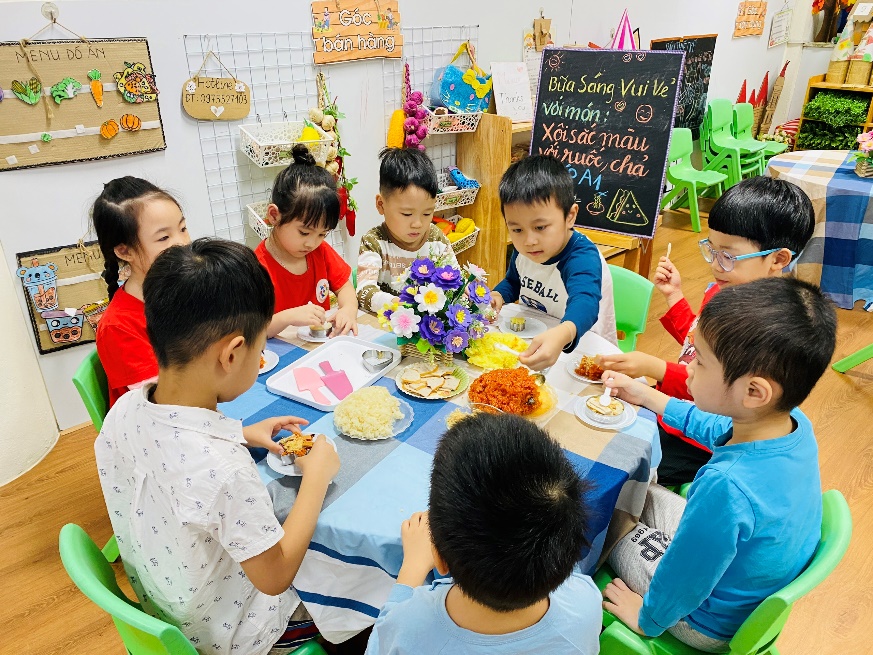 A group of children sitting at a table eating food

Description automatically generated
