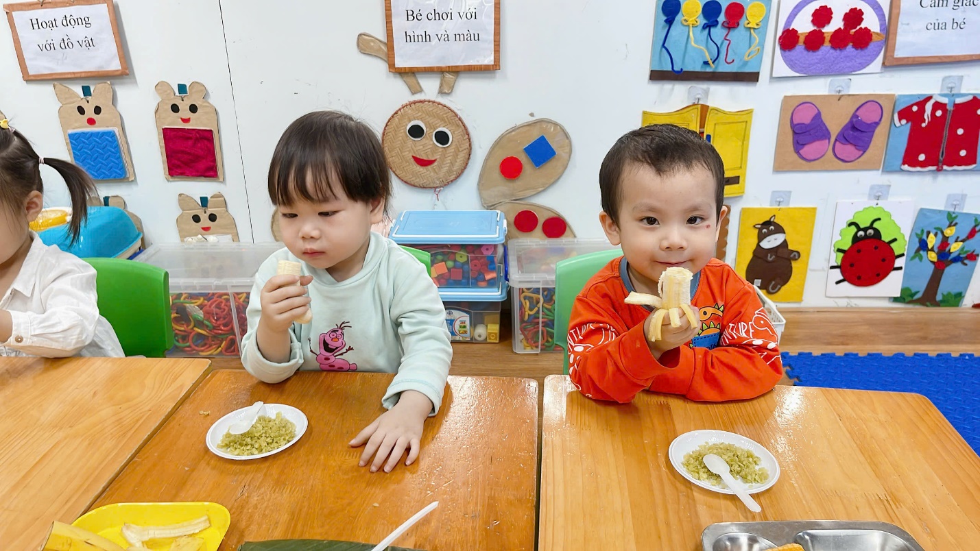 A couple of children eating at a table

Description automatically generated