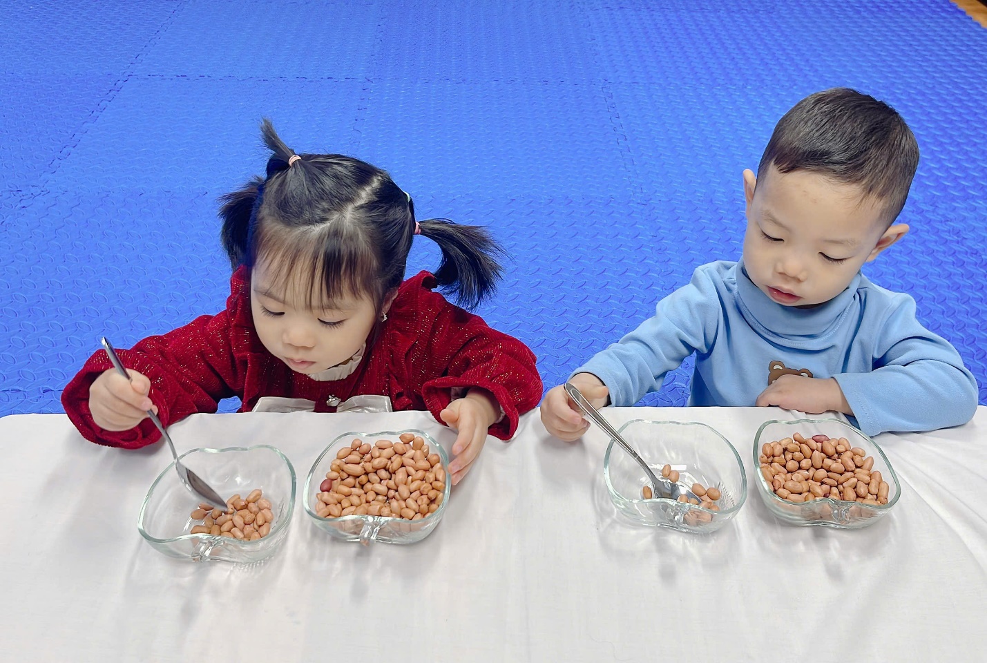 A couple of children eating peanuts

Description automatically generated