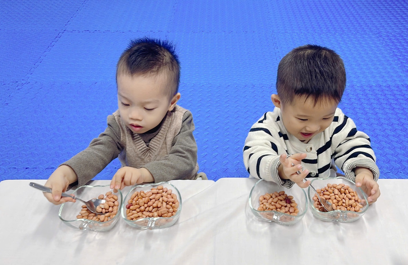 Two young boys sitting at a table with bowls of food

Description automatically generated