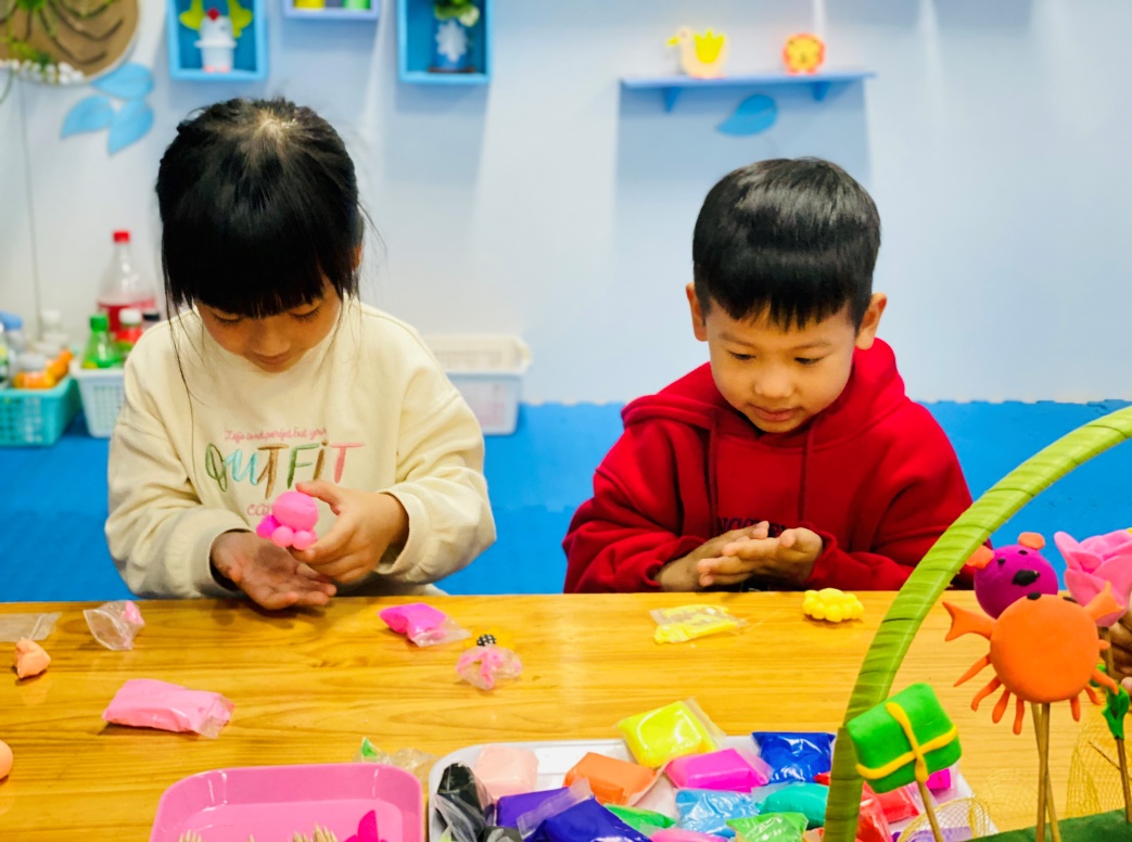 A child and child playing with clay
Description automatically generated