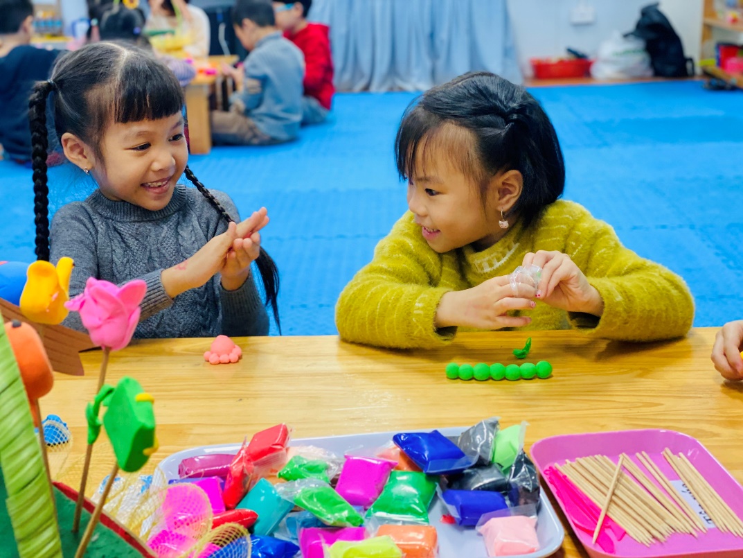 Two girls sitting at a table with colorful objects
Description automatically generated