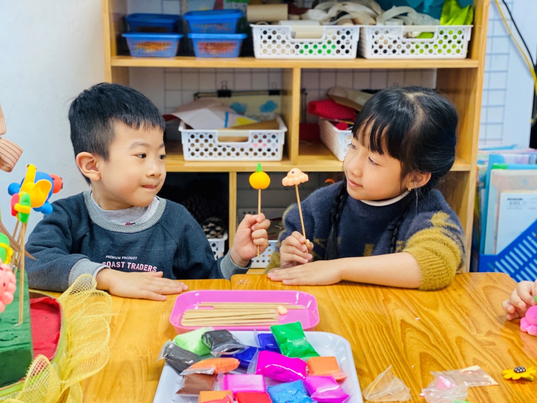 A child and child sitting at a table with food
Description automatically generated