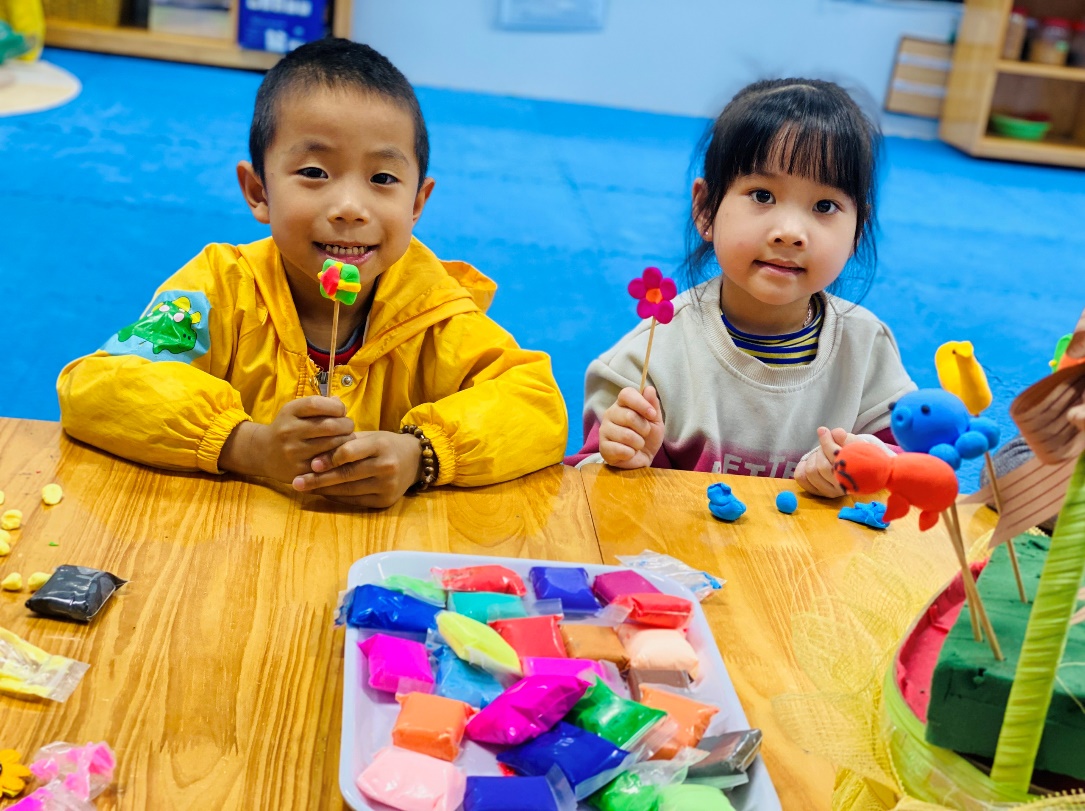 A child and child sitting at a table with clay
Description automatically generated