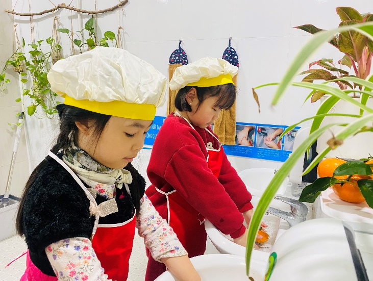 Two girls wearing chef hats and standing in a kitchenDescription automatically generated