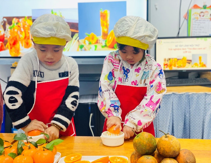 Two children in aprons cutting orangesDescription automatically generated