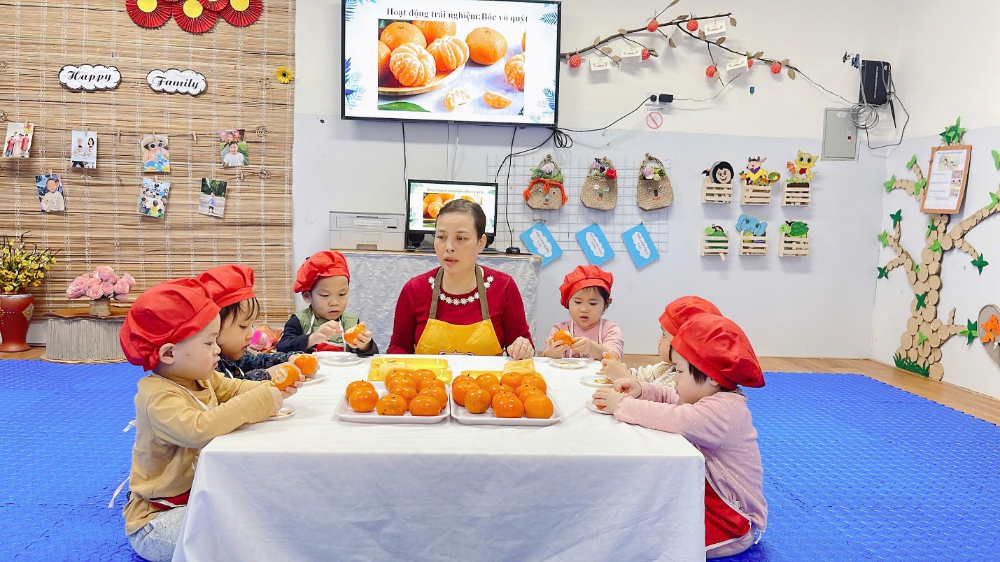 A group of children sitting at a table with oranges
Description automatically generated