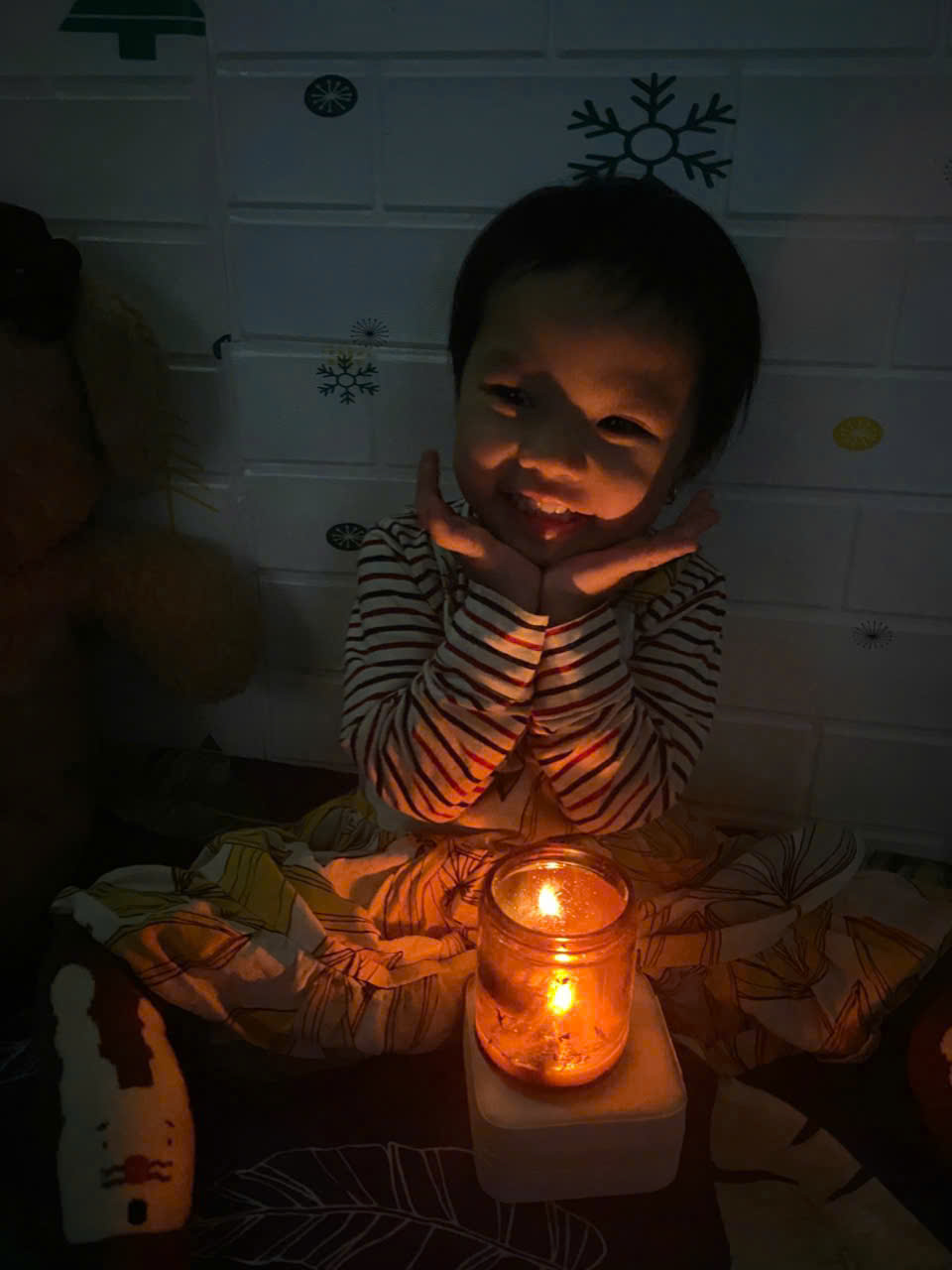 A child sitting in front of a lit candle
Description automatically generated