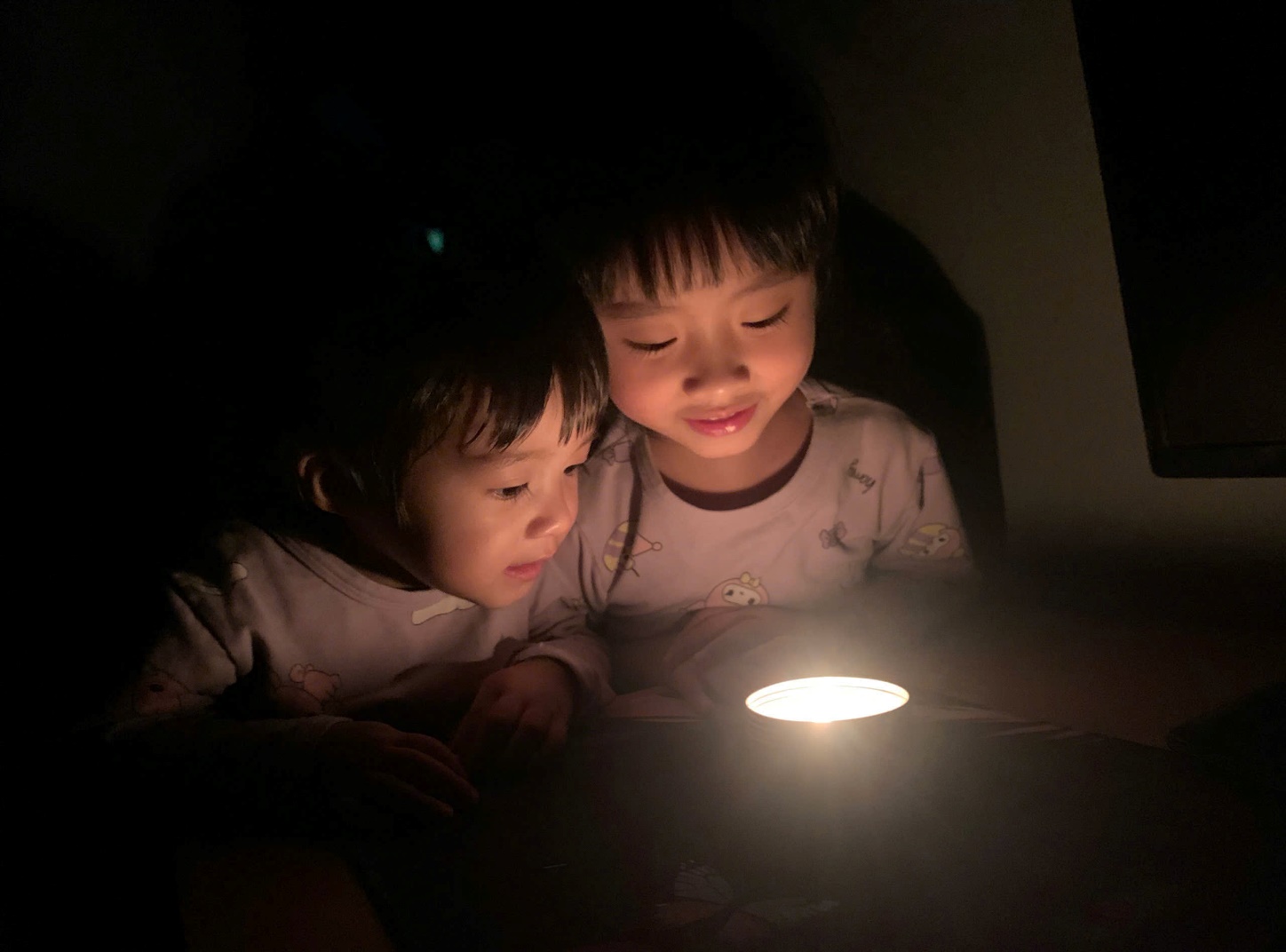 Two children looking at a candle
Description automatically generated